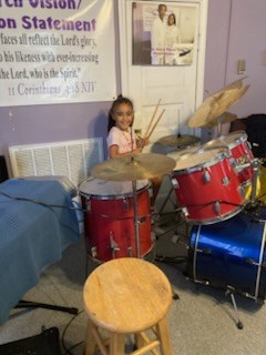 A young girl playing the drum set in the sanctuary