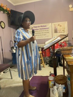 A woman in a striped dress speaking at the front of the sanctuary